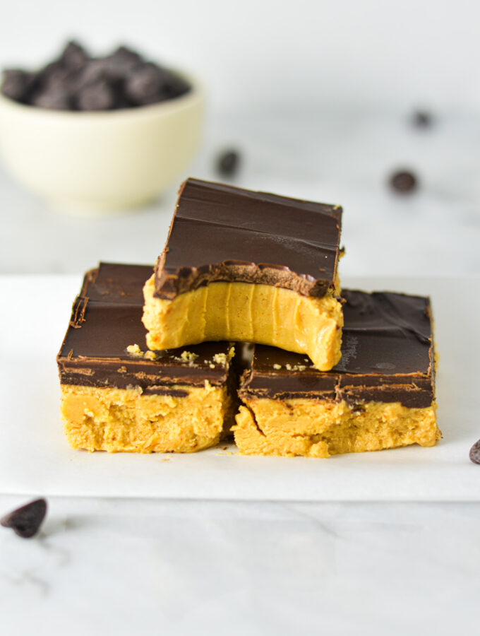 Rich Buckeye Bars neatly stacked with a bite taken out of the top no bake bar.