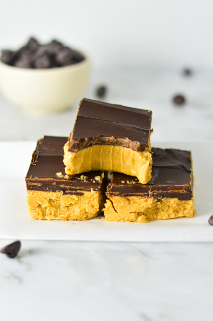 Rich Buckeye Bars neatly stacked with a bite taken out of the top no bake bar.