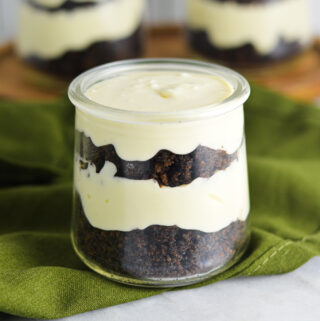 Three Chocolate Cake Cheesecake Cups in small glass containers. Each individual dessert is layered with dark brown chocolate cake and no bake cheesecake.