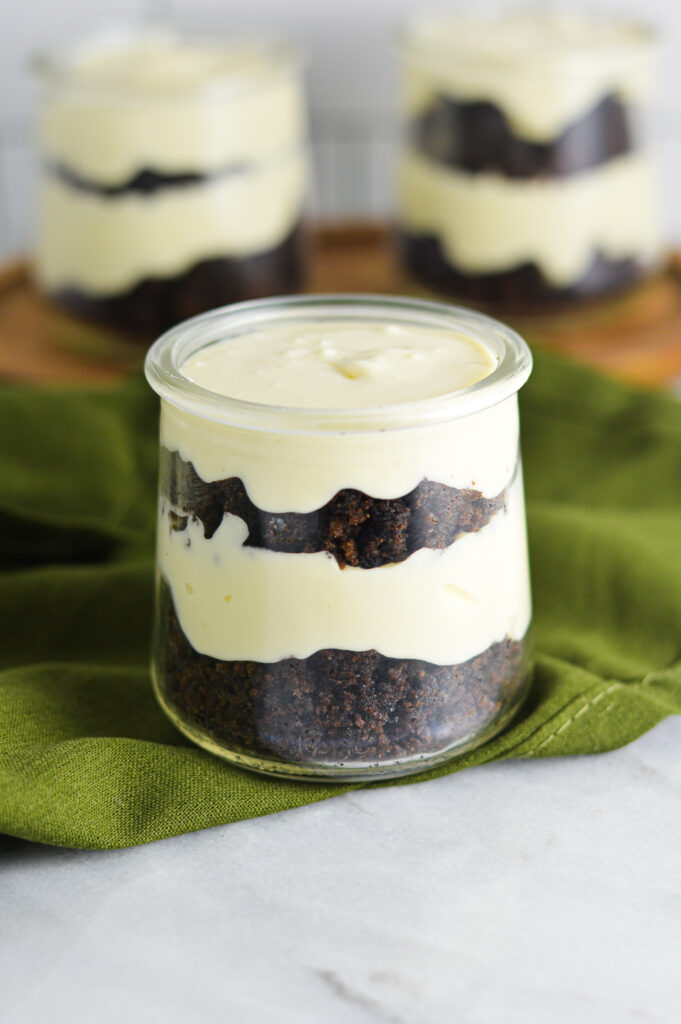 Three Chocolate Cake Cheesecake Cups in small glass containers. Each individual dessert is layered with dark brown chocolate cake and no bake cheesecake.