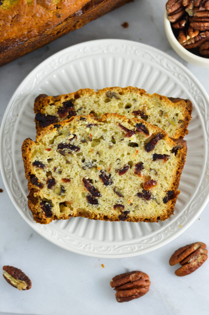 Cranberry Pecan Banana Bread slices on a white ceramic plate.