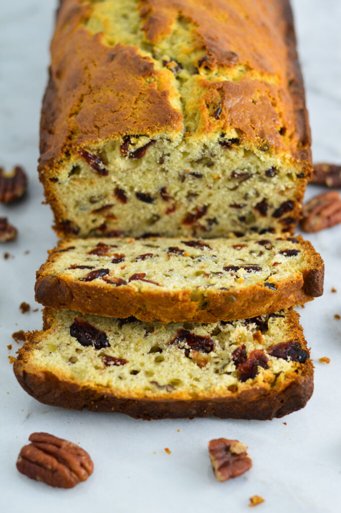 A Cranberry Pecan Banana loaf sliced on a white granite surface.