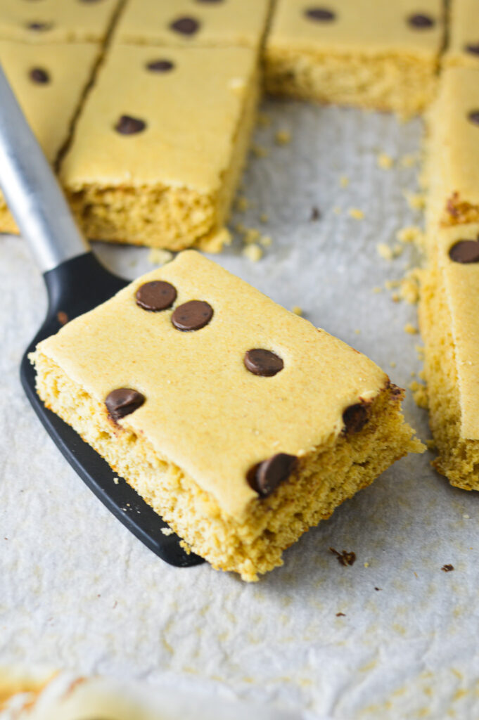 A spatula holding a Chocolate Chip Sheet Pan Pancake on a parchment paper lined baking sheet.