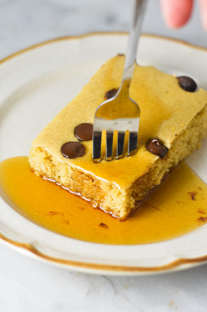 A fork inserted into a Chocolate Chip Sheet Pan Pancake, showing the soft and fluffy inside.