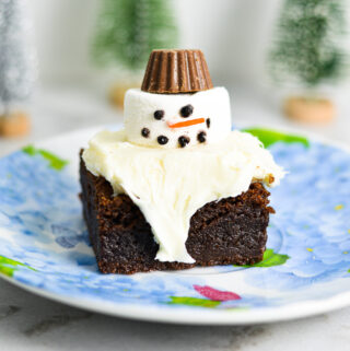 Melted Snowman Nutella Brownies with white frosting on top of a fudgy Nutella brownie. A small peanut butter cup is used for the marshmallow snowman's hat.