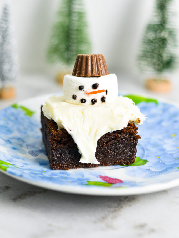 Melted Snowman Nutella Brownies with white frosting on top of a fudgy Nutella brownie. A small peanut butter cup is used for the marshmallow snowman's hat.