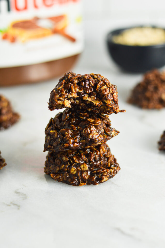 A stack of rich chocolate No Bake Nutella Oatmeal Cookies with a bite taken out of the top cookie.