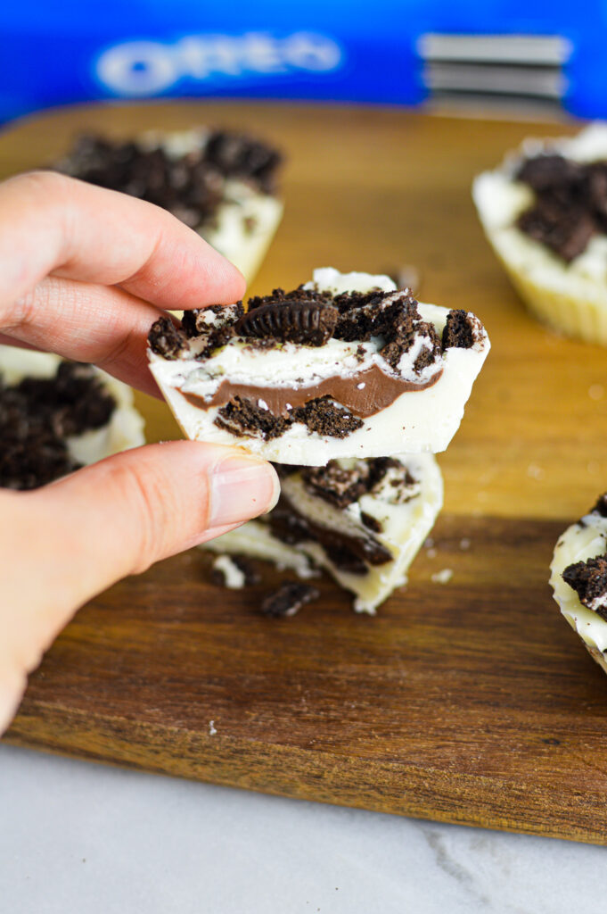 A hand holding a white chocolate Nutella Stuffed Oreo Cup.