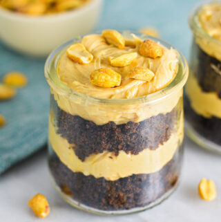 Rich Peanut Butter Chocolate Cake Cheesecake Cups in small glass containers. Layers of creamy cheesecake and rich chocolate cake all topped with crunchy peanuts.