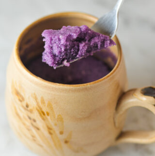 A fork taking a scoop out of a vibrant purple Taro Mug Cake.