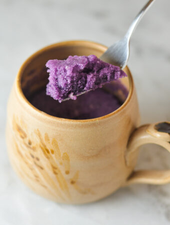 A fork taking a scoop out of a vibrant purple Taro Mug Cake.