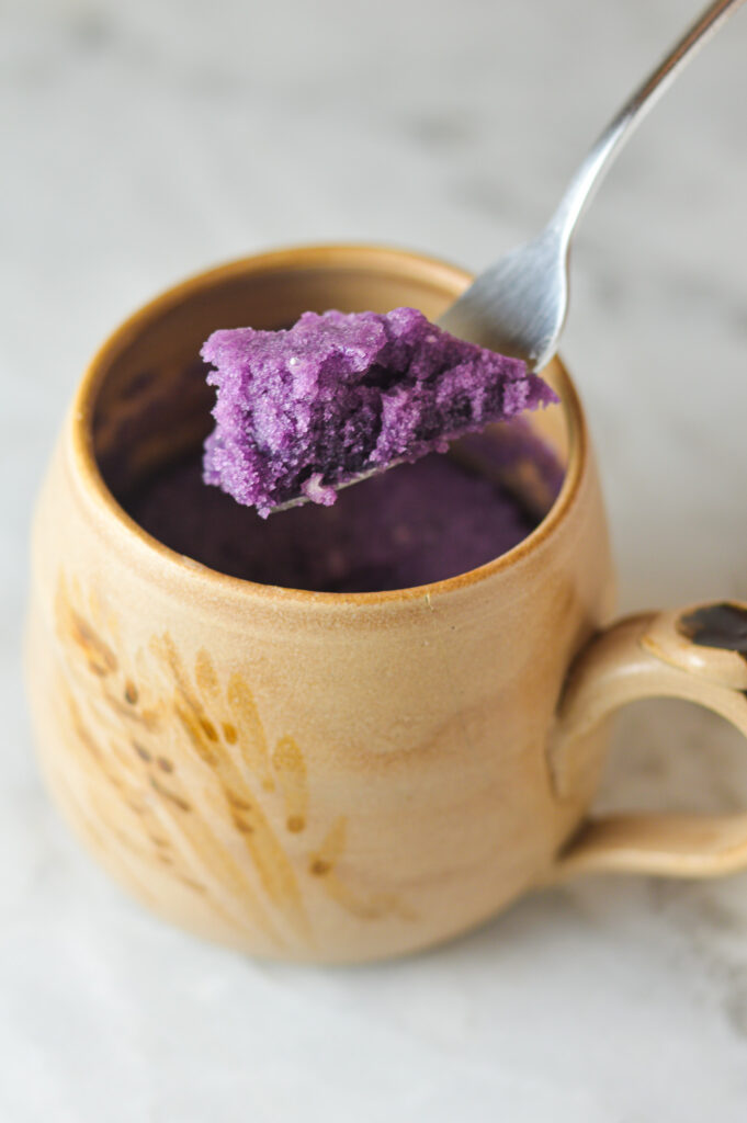 A fork taking a scoop out of a vibrant purple Taro Mug Cake.