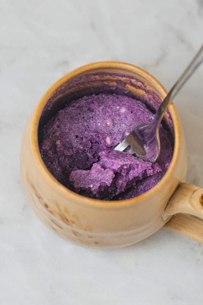 A fork in a large mug with some Taro Mug Cake in it.