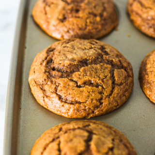 A batch of Yogurt Nutella Muffins in a muffin tin, clearly revealing the cracked tops.