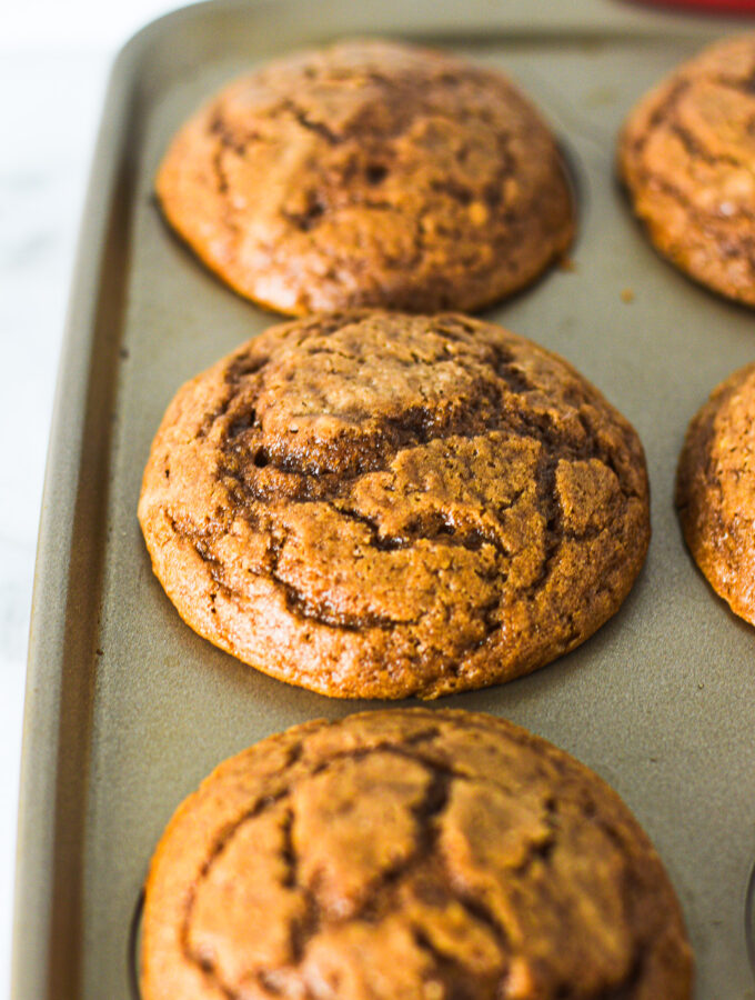 A batch of Yogurt Nutella Muffins in a muffin tin, clearly revealing the cracked tops.