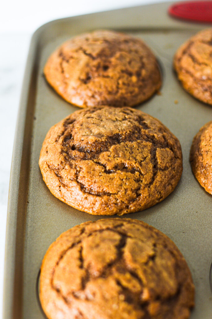 A batch of Yogurt Nutella Muffins in a muffin tin, clearly revealing the cracked tops.