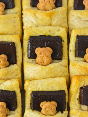 Bears in a Blanket wrapped in golden brown crescent roll dough with a piece of dark chocolate as the graham cracker bear's pillow.