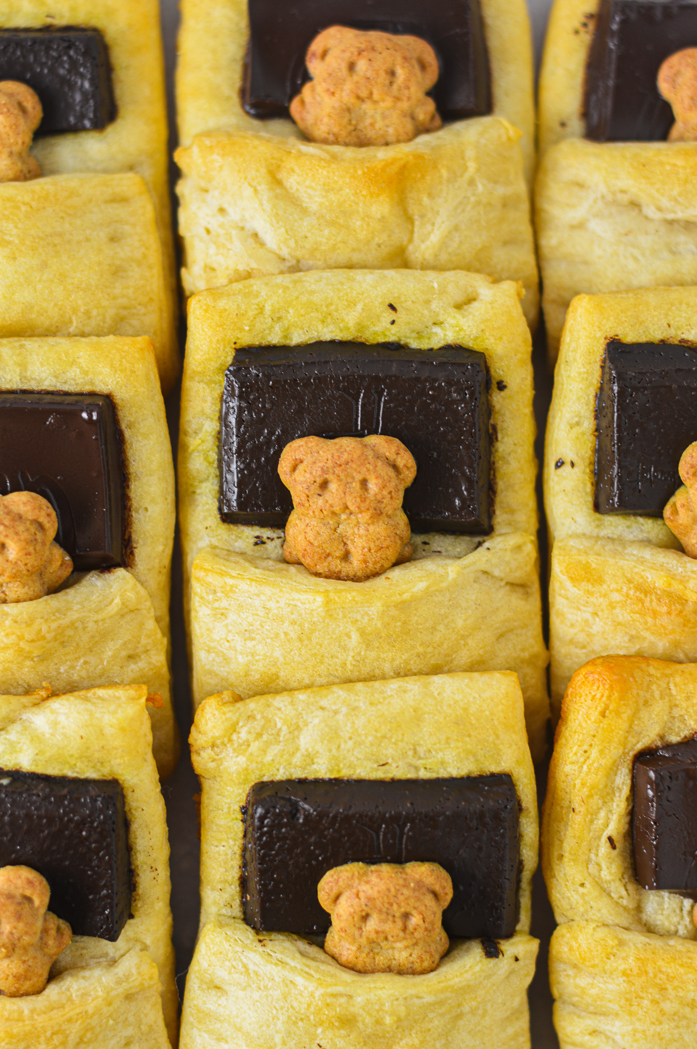 Bears in a Blanket wrapped in golden brown crescent roll dough with a piece of dark chocolate as the graham cracker bear's pillow.