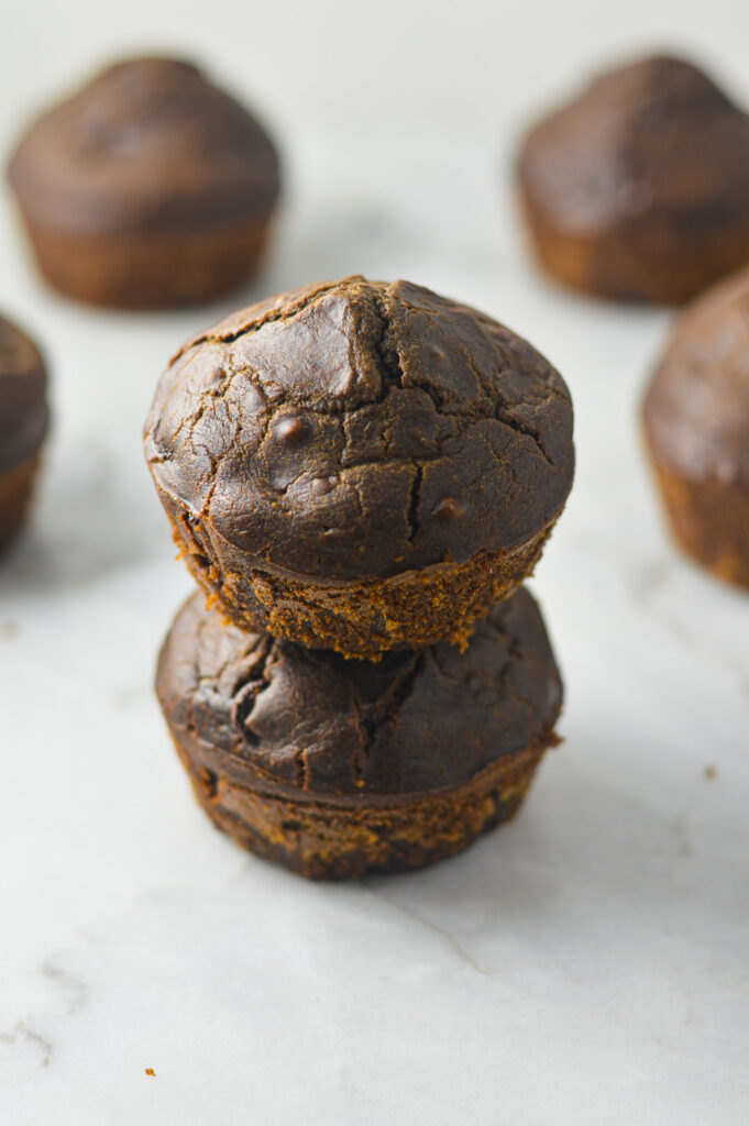 A stack of Healthy Mocha Muffins with the top of the muffins slightly cracked, hinting at the moist and fluffy interior.