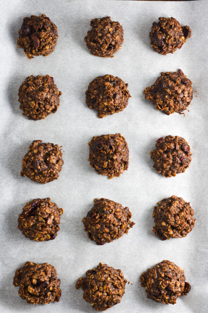 A parchment paper lined baking pan with No Bake Nutella Cranberry Oatmeal Cookies arranged in rows.