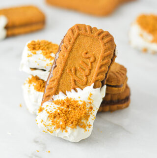 Nutella Biscoff Sandwiches on a granite surface. The Lotus Biscoff Cookie sandwiches are dipped in white chocolate and sprinkled with crushed biscoff cookies.