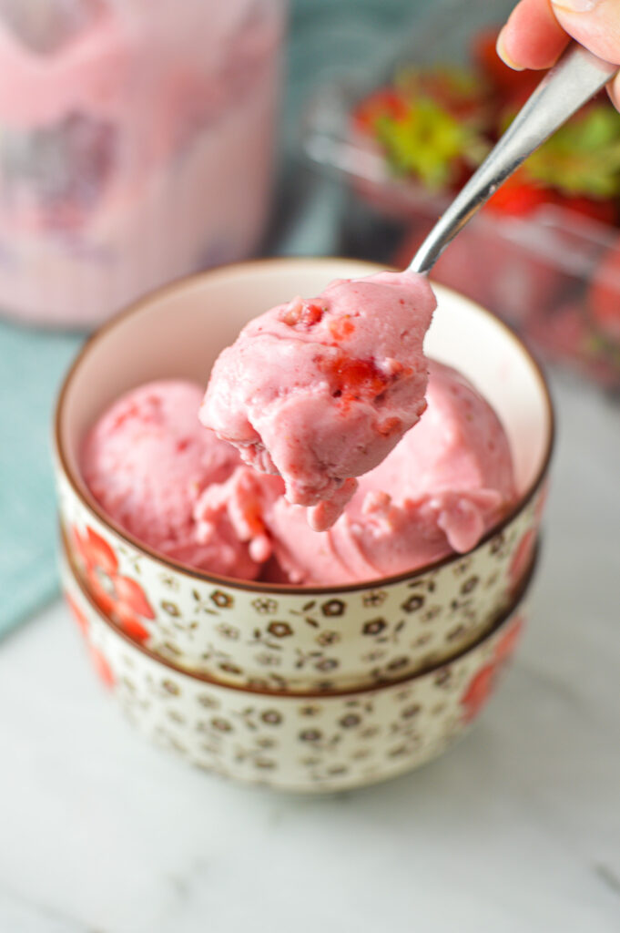 A small spoon scooping out some 3 Ingredient Ninja Creami Strawberry Ice Cream from a small bowl.