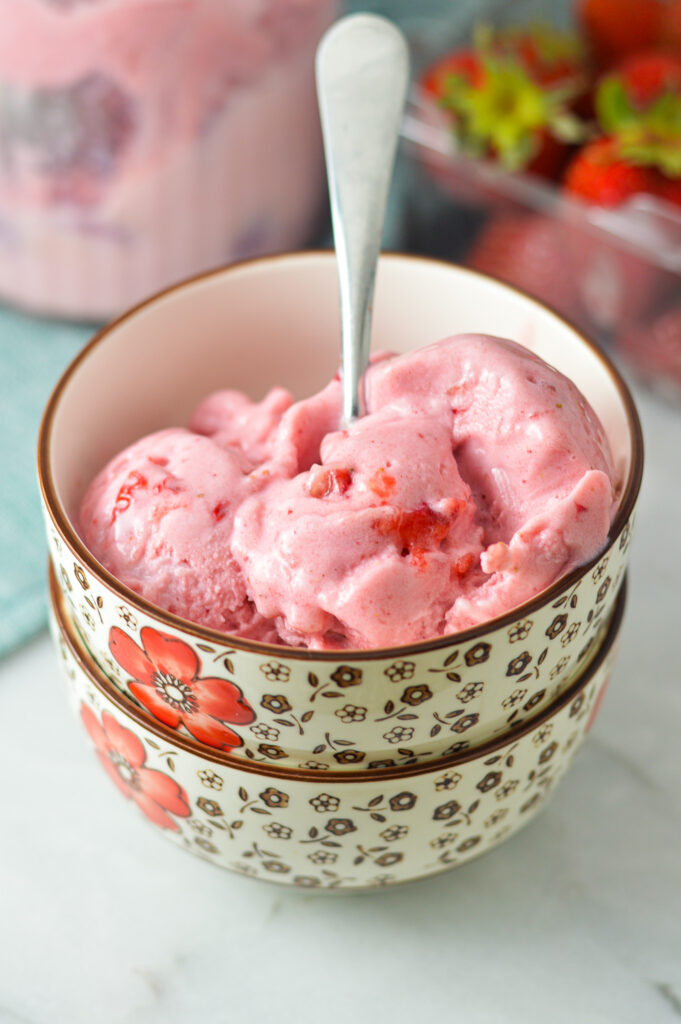 A spoon sticking straight out of a bowl full of creamy Strawberry Ninja Creami ice cream.