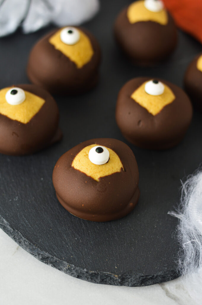 Some Eyeball Buckeyes on a black tray with some spiderwebs and spiders in the background, giving it a creepy Halloween feel.