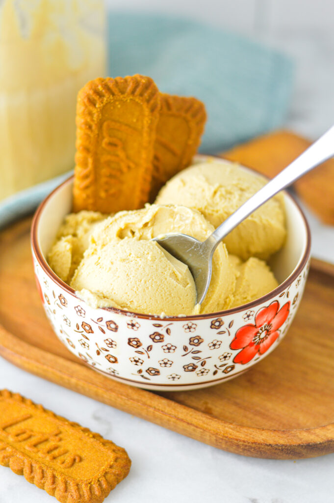 A bowl of Ninja Creami Biscoff Ice Cream with a small spoon taking a scoop of the creamy dessert.