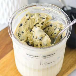 A Ninja Creami pint filled with Ninja Creami Chocolate Chip Protein Ice Cream, with a spoon inside ready to scoop.