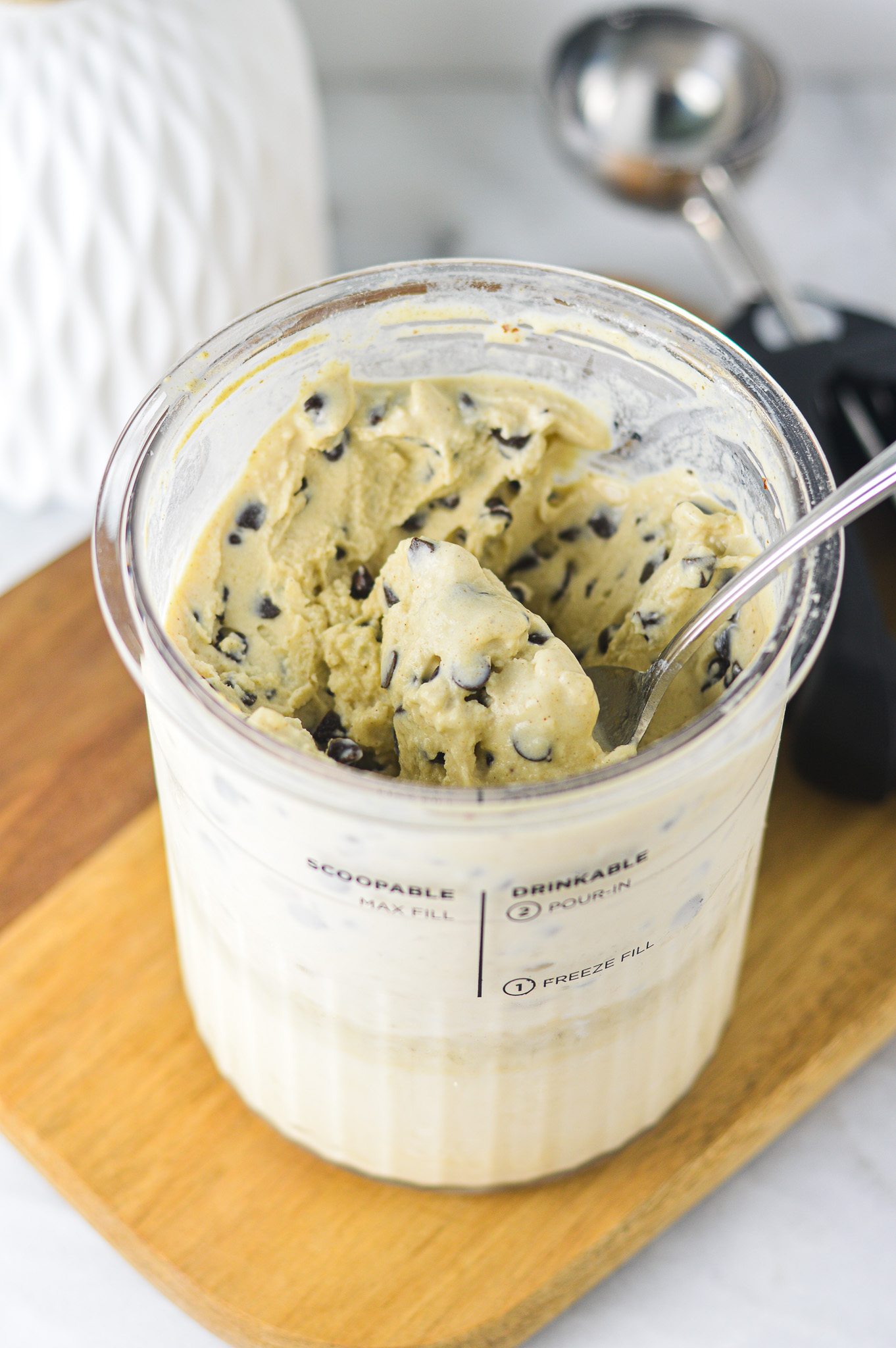 A Ninja Creami pint filled with Ninja Creami Chocolate Chip Protein Ice Cream, with a spoon inside ready to scoop.