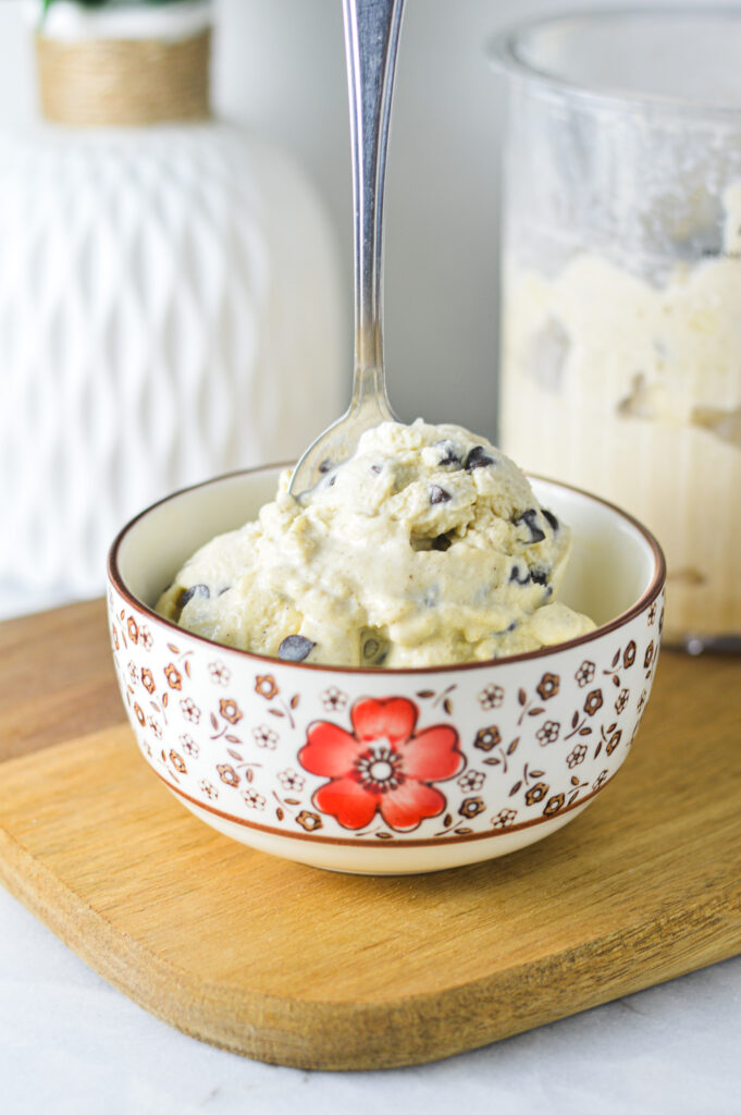 A bowl full of Ninja Creami Chocolate Chip Protein Ice Cream with a spoon sticking out of the mini chocolate chip filled dessert.