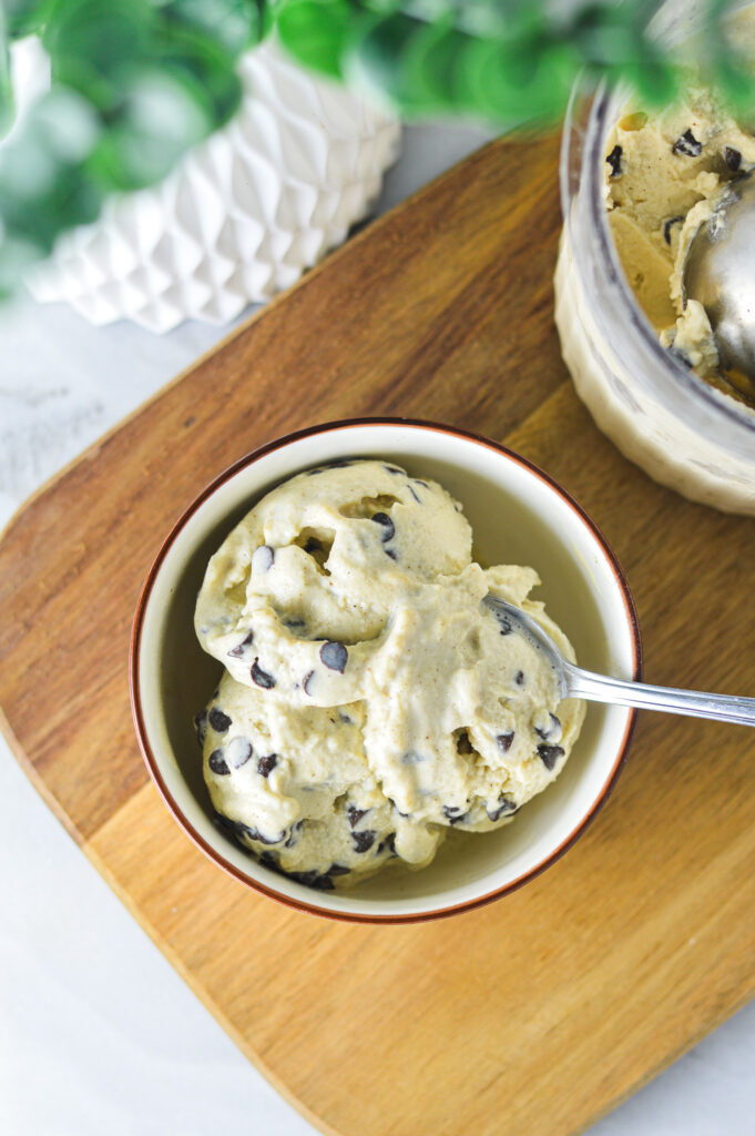 Overhead shot of a small bowl of Ninja Creami Chocolate Chip Protein Ice Cream, with the Deluxe Ninja Creami pint beside it.