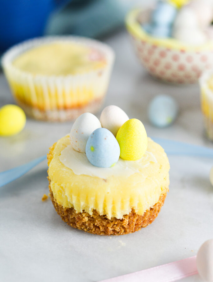 Easter Egg Mini Cheesecakes with a graham cracker crust base and topped with pastel colored chocolate eggs.