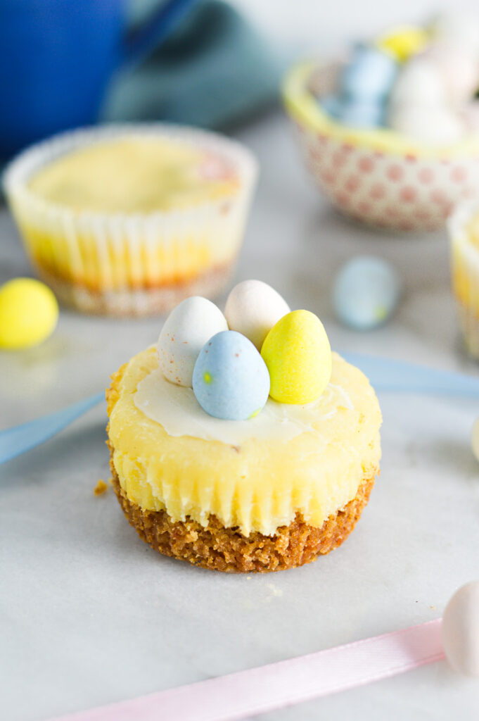 Easter Egg Mini Cheesecakes with a graham cracker crust base and topped with pastel colored chocolate eggs.