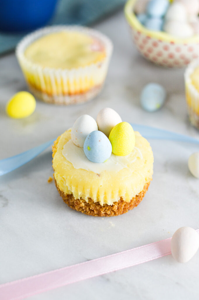 Some Easter Egg Mini Cheesecakes, with mini eggs in the background.