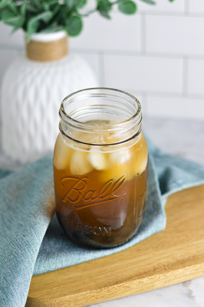 Honey Green Bubble Tea in a ice filled mason jar on a wooden board.