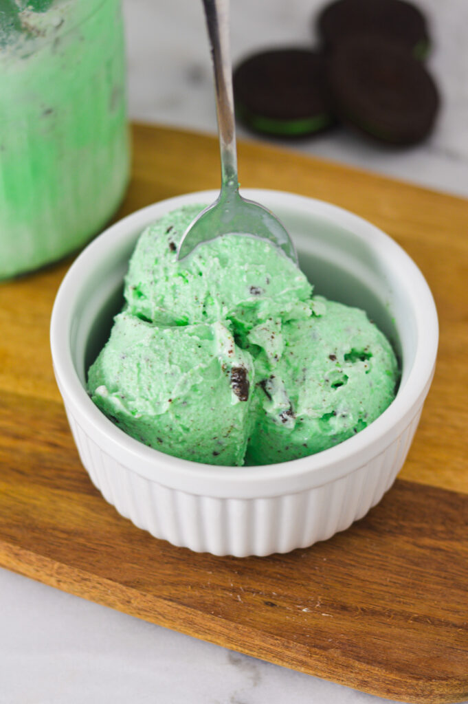 A bowl of Ninja Creami Mint Oreo Ice Cream with a spoon taking a scoop of ice cream out of the bowl.