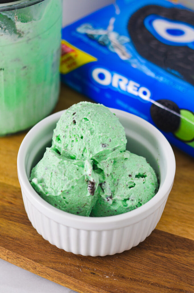 Ninja Creami Mint Oreo Ice Cream with the Ninja Creami pint and mint Oreos in the background.