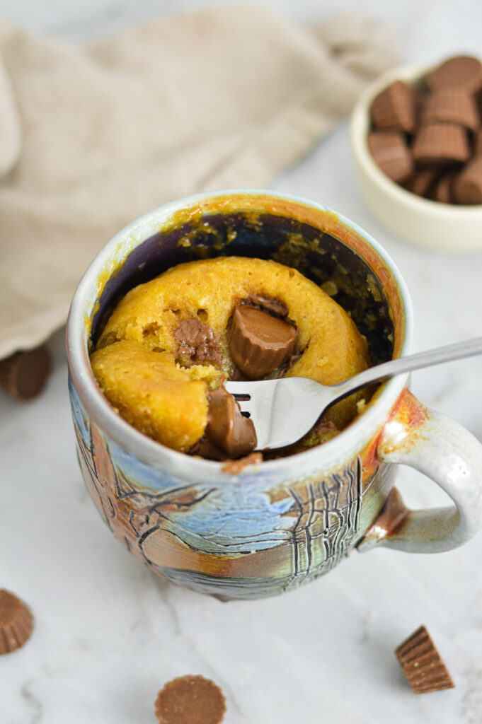 A fork taking a fluffy bite out of the Peanut Butter Cup Mug Cake.