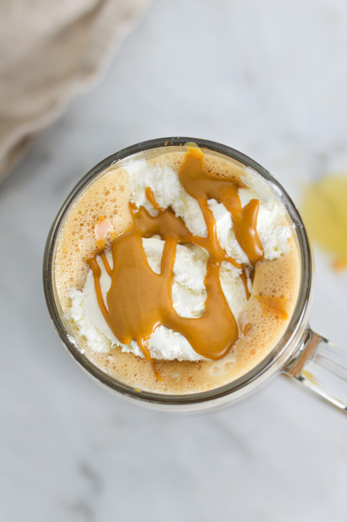 A glass cup filled with Peanut Butter Mocha, topped with whipped cream and a drizzle of peanut butter sauce.