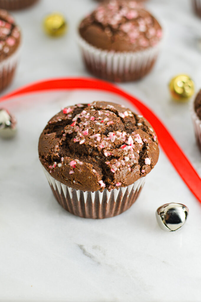 Peppermint Creamer Chocolate Muffins, with some silver and gold bells and red ribbon giving it a Christmas feel.