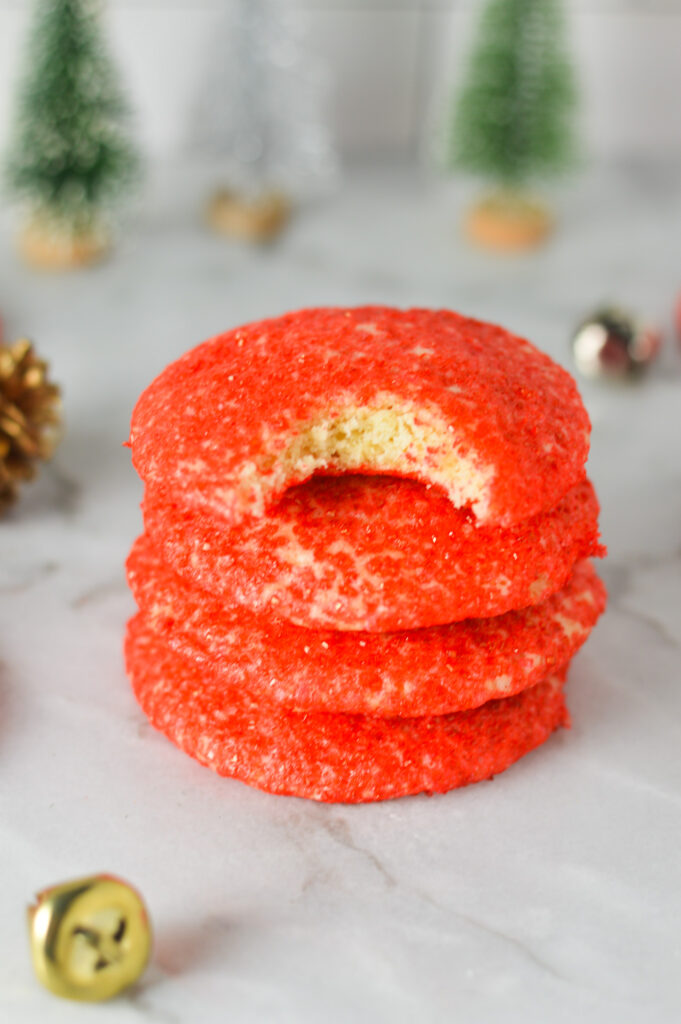 A stack of festive Peppermint Sprinkle Cookies with a bite taken out of the top cookie.