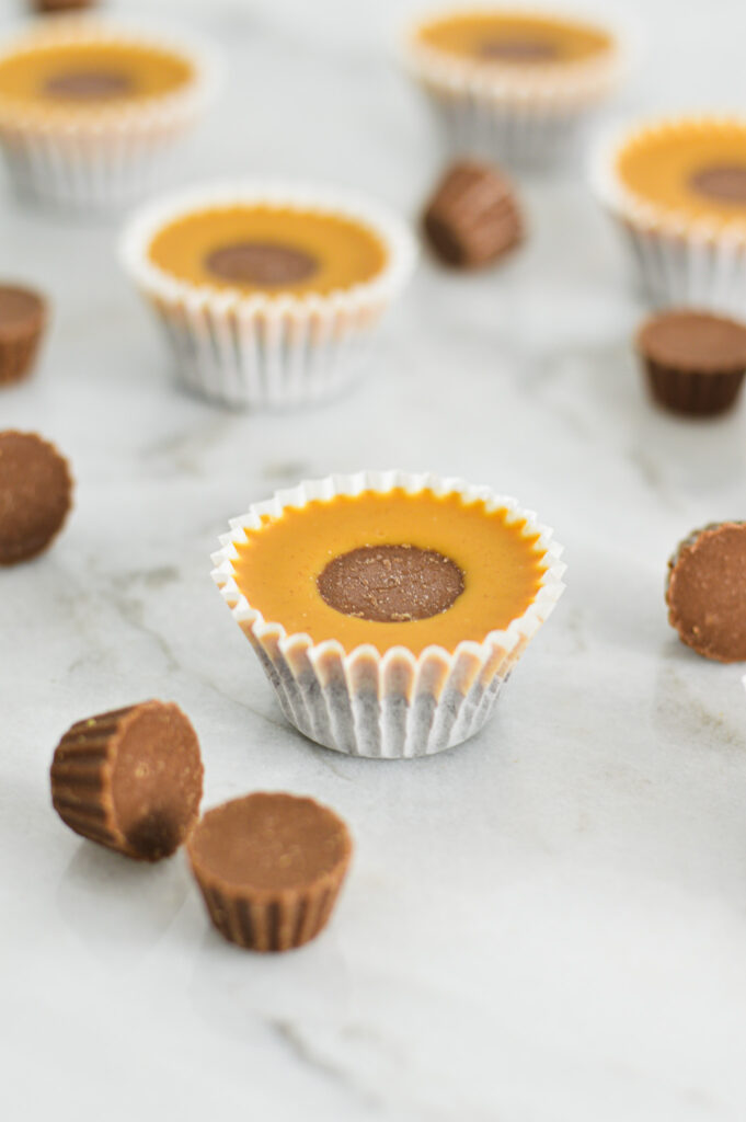 A couple of Reese's Peanut Butter Nutella Cups in mini cupcake liners, with mini peanut butter cups scattered around them.