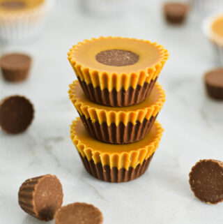 A stack of creamy Reese's Peanut Butter Nutella Cups, with defined Nutella and peanut butter layers and a mini Reese's cup peaking out of the top layer.