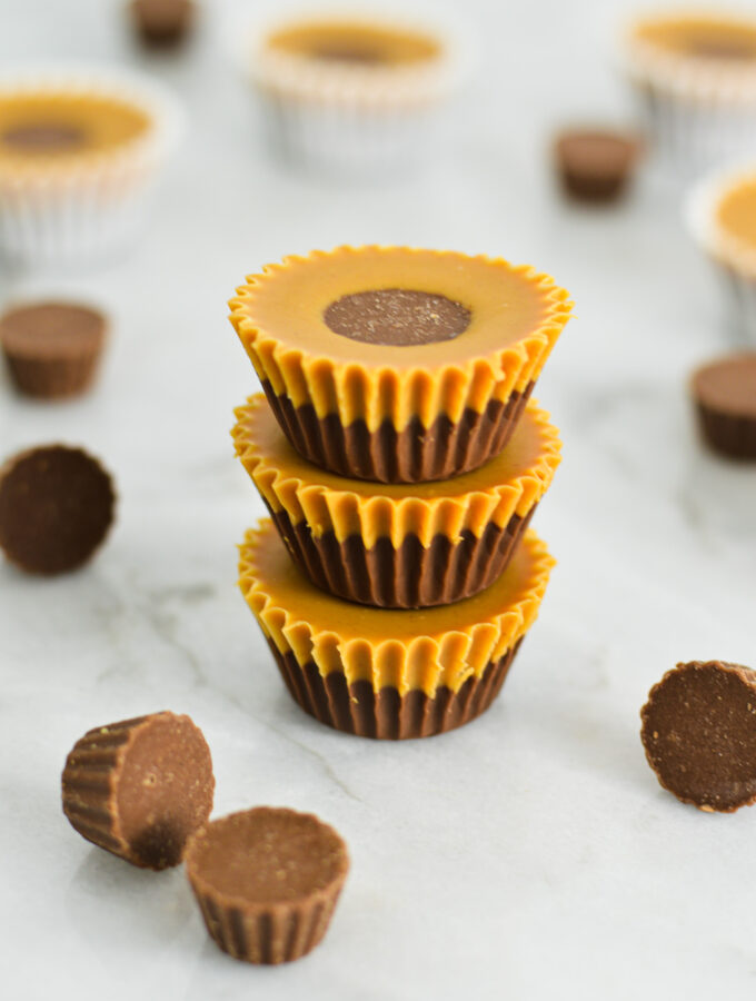 A stack of creamy Reese's Peanut Butter Nutella Cups, with defined Nutella and peanut butter layers and a mini Reese's cup peaking out of the top layer.