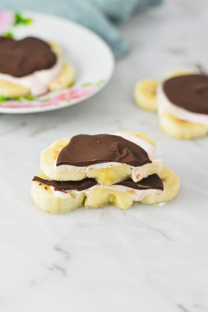 Mini Chocolate Banana Yogurt Bark cut in half and stacked, to show the layers of banana coins, flavored yogurt and hardened chocolate.