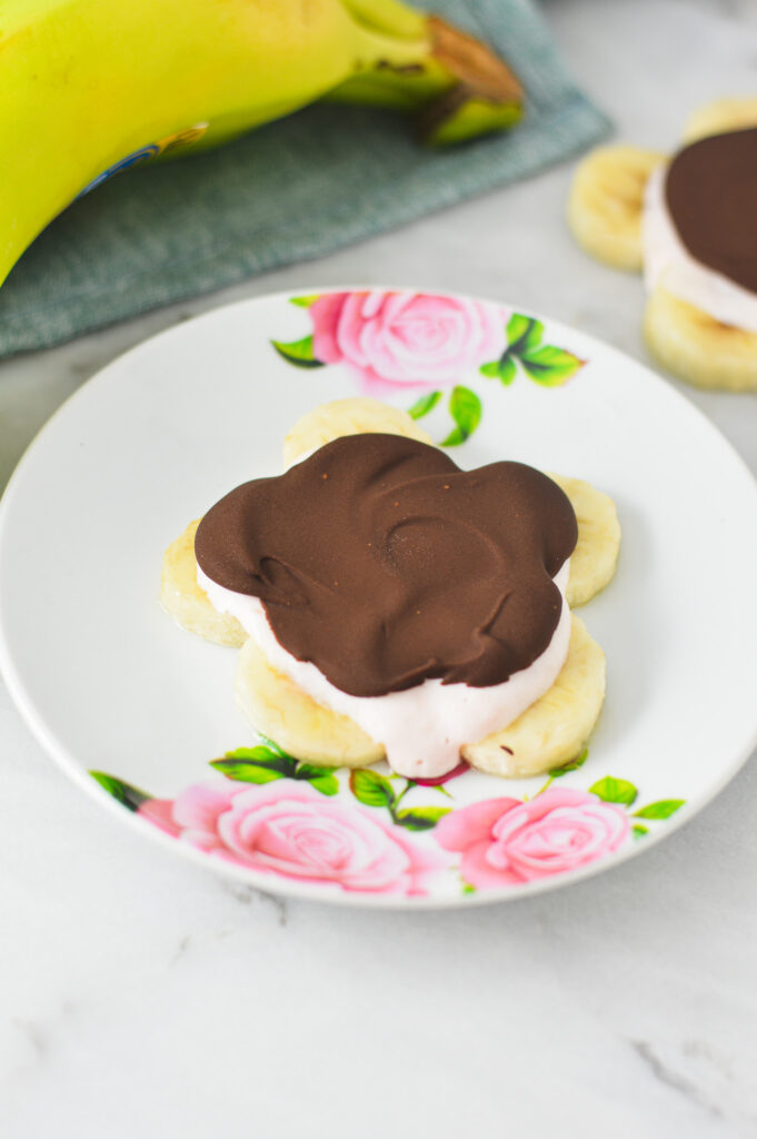 Mini Chocolate Banana Yogurt Bark on a small plate, with a banana in the background.