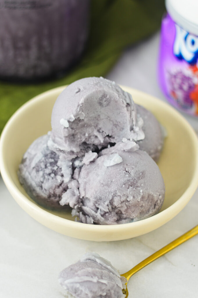 A bowl full of scoops of Ninja Creami Kool-Aid Italian Ice. The top scoop has a spoonful taken out, showing the smooth and slightly icy texture.