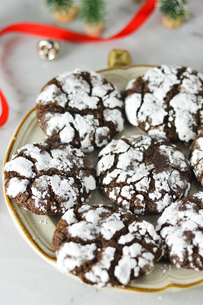 A plate of Peppermint Chocolate Crinkle Cookies, featuring chocolatey cookies with a cracked powdered sugar coating.